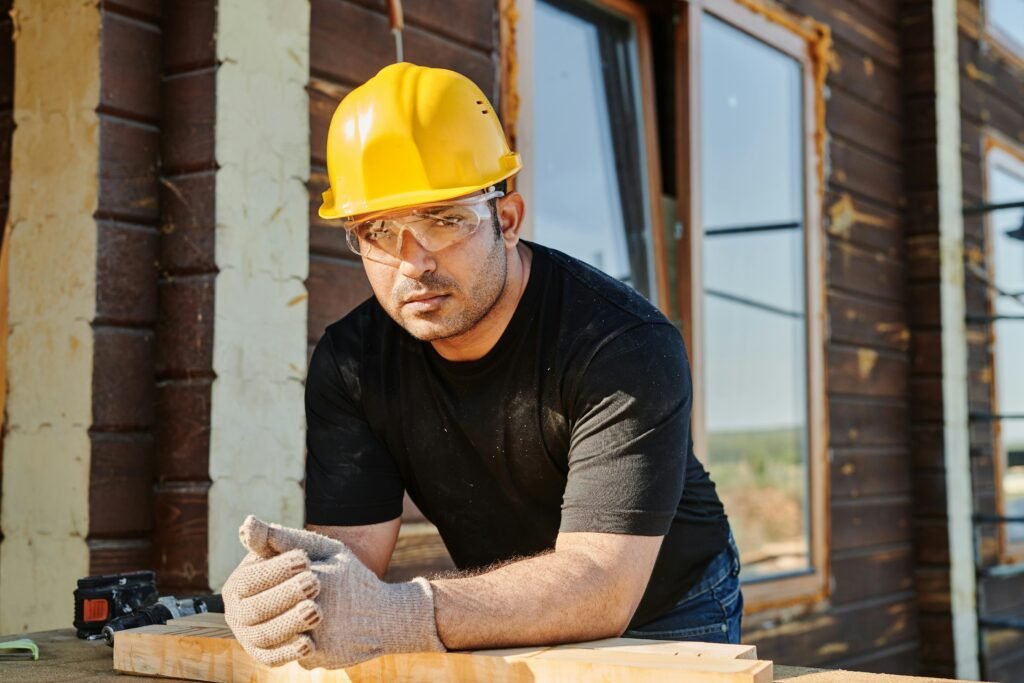Focused construction worker with safety gear at a woodwork site.